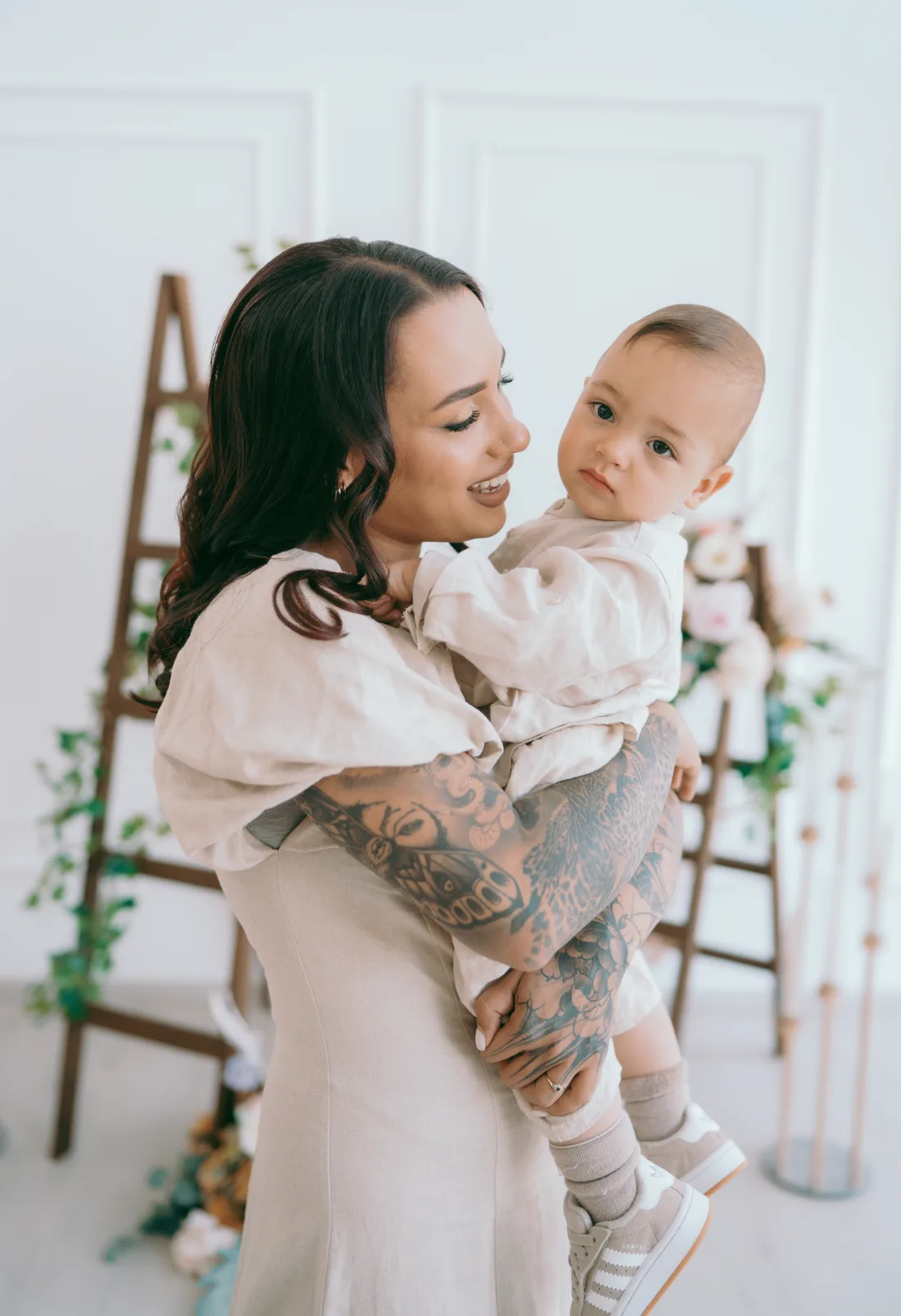 Naomi Crawford looking at her son Theodoros as she holds him, both dressed in pale linen.
